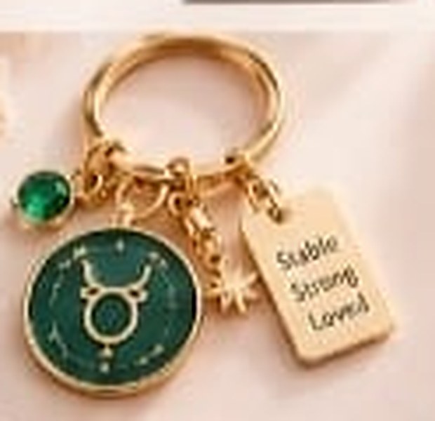 Taurus zodiac keychain with a gold ring, enamel sign disc, crystal, star charm and tag reading Stable Strong Loved